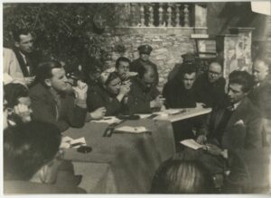 Jean Blot (assis, prenant des notes, pour une mission d'observation) dans le camp des réfugiés politiques de Syros (vers 1947).Crédit image : Archives Jean Blot / IMEC